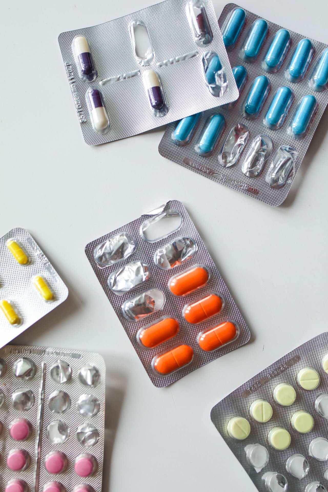 Assorted blister packs of capsules and tablets on a white surface
