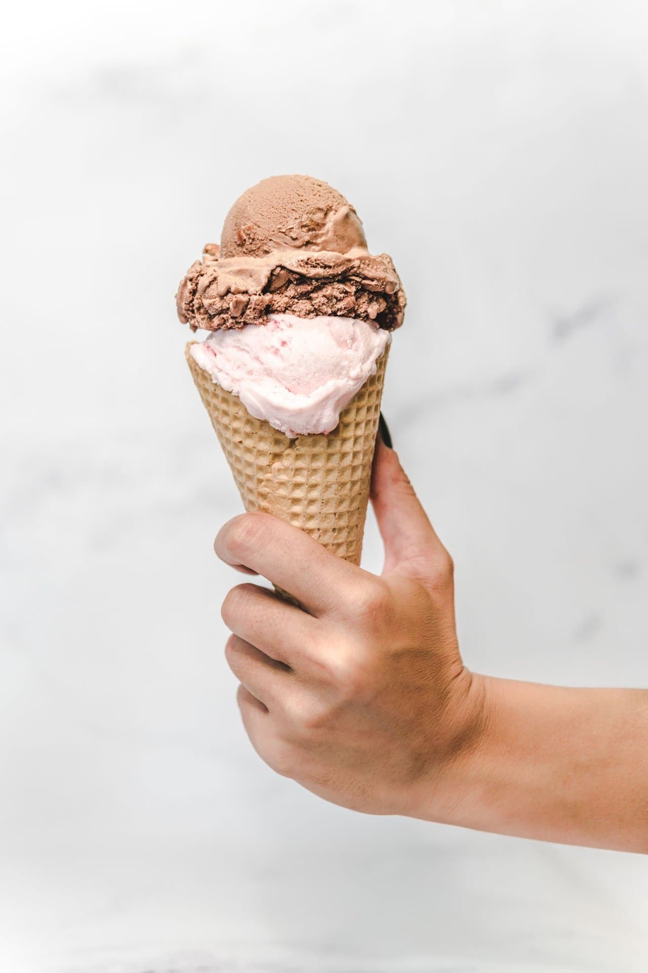 Close-up of a person holding an ice cream cone, a common trigger for sensitive teeth