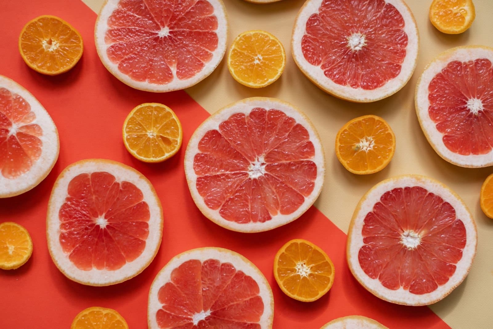 Sliced citrus fruits including grapefruit and oranges arranged on a colourful background