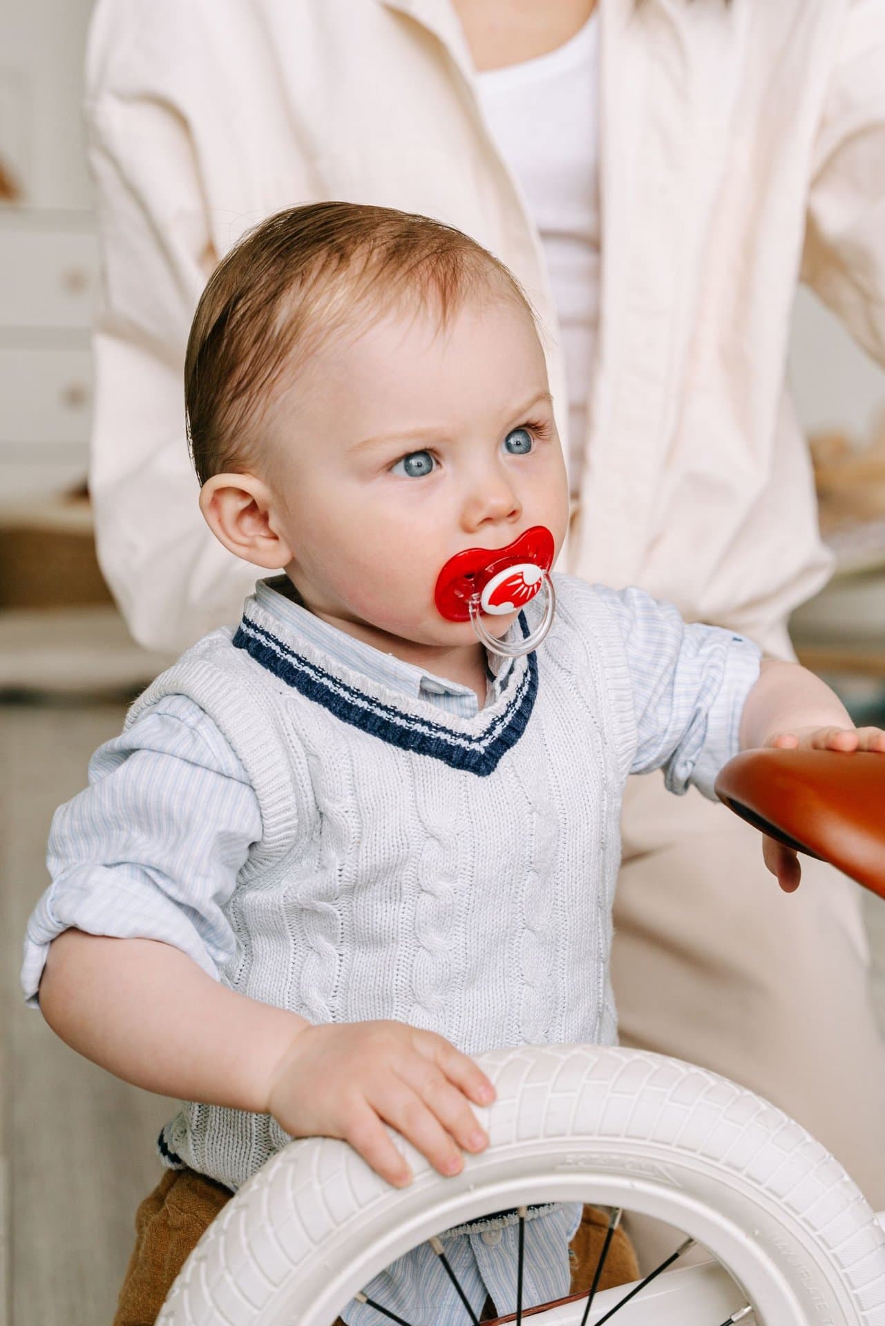 Toddler with a pacifier in their mouth being held by a parent
